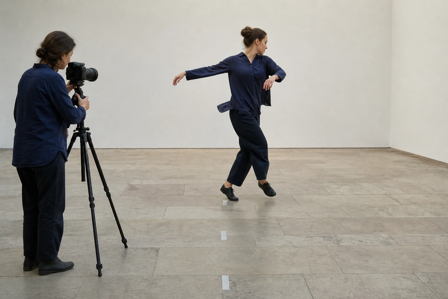 Bildforscherin fotografiert aus fester Kameraposition eine Performerin im Drehschritt entlang markierter Bodenpunkte